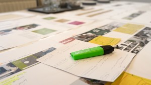 Planungsprozess und Strategieentwicklung mit Fokus auf Printmaterialien und Notizen, dargestellt auf einem Agenturtisch.