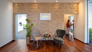 Empfangsbereich der ude Werbeagentur mit Firmenlogo an einer Steinwand, stilvollen Sitzmöglichkeiten und einer einladenden Atmosphäre.